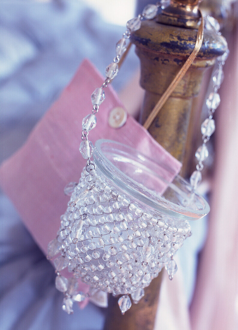 Nahaufnahme eines perlenbesetzten Nachtlichts und einer hübschen rosa Tasche, die an einem hölzernen Bettpfosten hängt