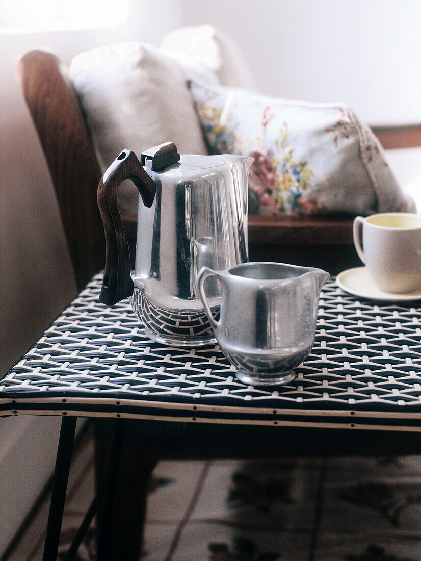 Picquotware-Kaffeekanne und -Milchkännchen aus Aluminiumguss auf geflochtenem schwarz-weißem Kunststofftisch