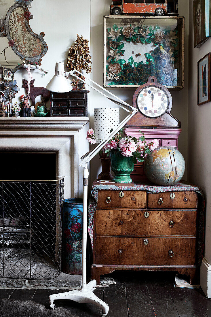 Set von hölzernen Schubladen neben dem Kamin mit Vintage-Sammlung von Objekten, darunter ein gemaltes rosa Schubladen Kunstwerk in einer glasierten Box 1920er Jahre Fortune Teller und achtzehnten Jahrhundert Globus
