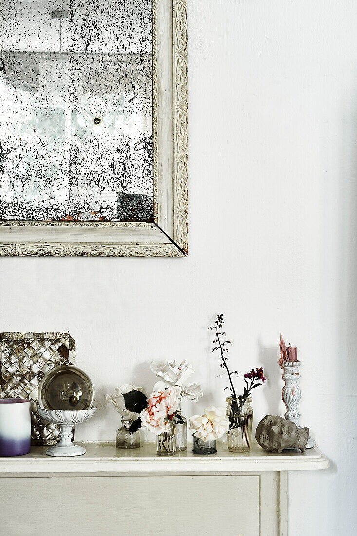 Ein schlanker Kaminsims in der Küche, auf dem Feen und kleine Gegenstände ausgestellt sind, mit einem französischen Spiegel mit Stockflecken