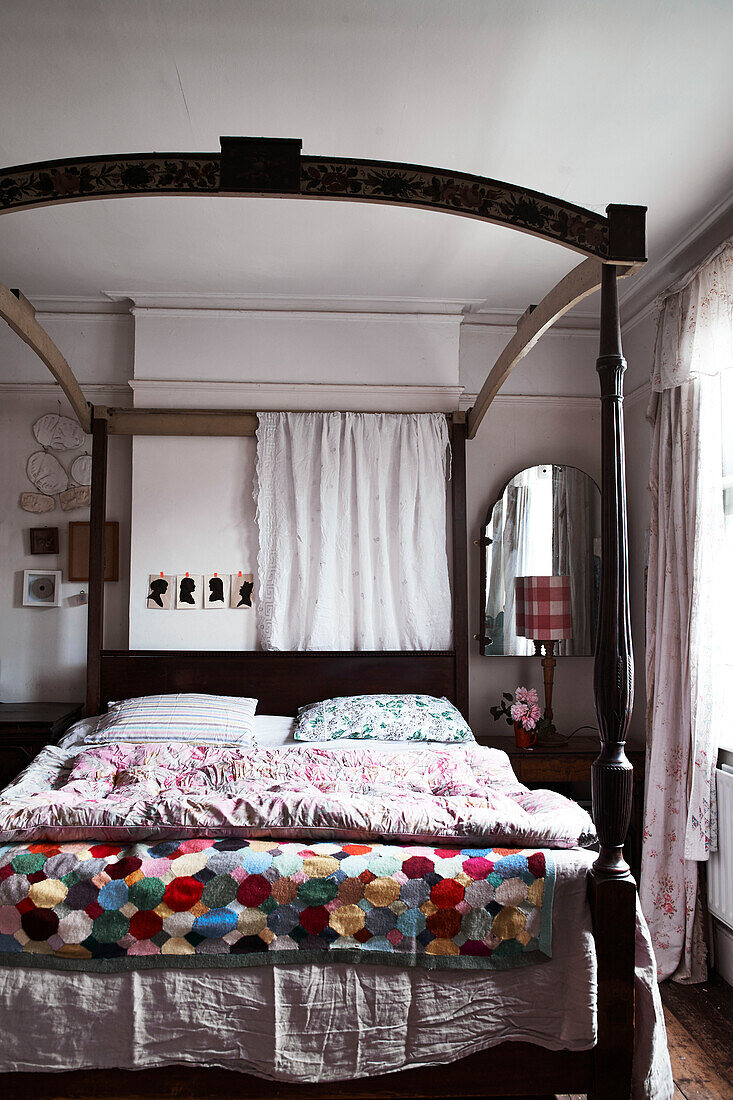 Four poster bed with a mix of crochet patchwork wool throws dainty floral and stripped bedding and eiderdowns panels of hanging lace and vintage french linen sheets creates a wonderful mix of patterns and textures in the main bedroom