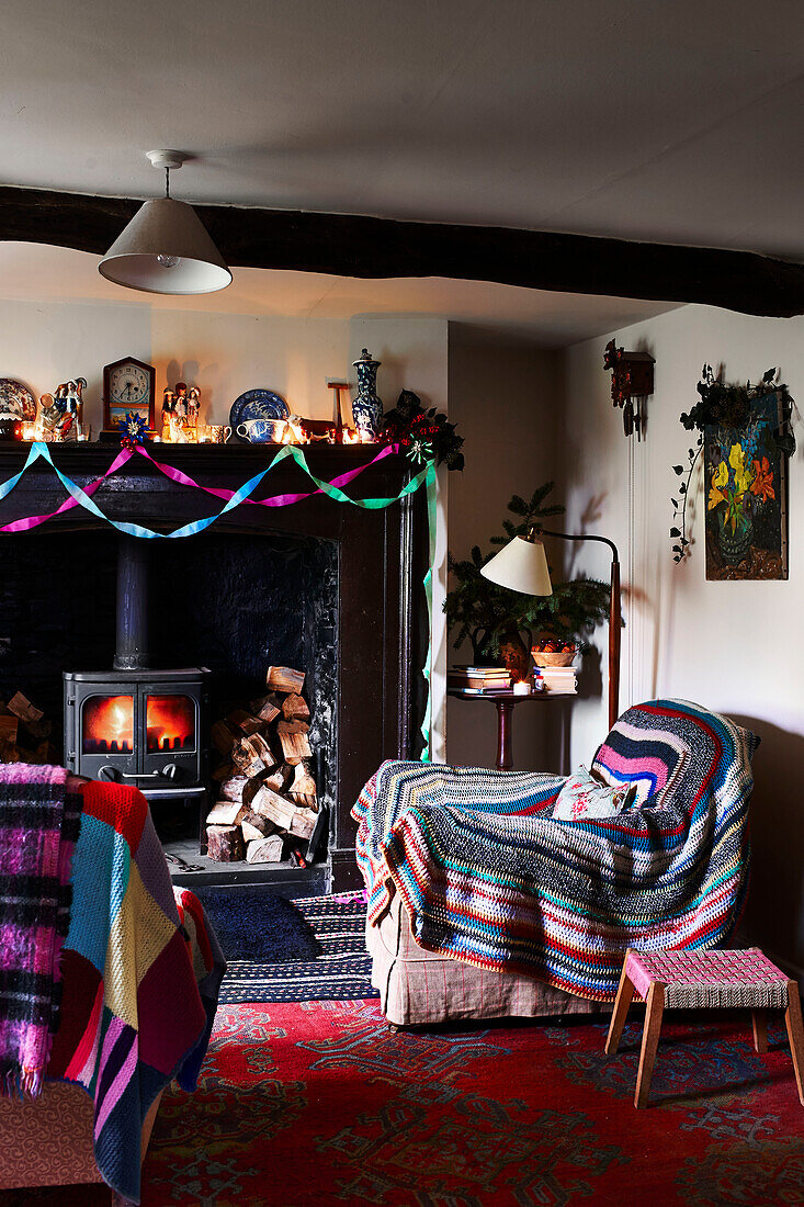 Crochet blanket over armchair at lit fireside in Shropshire living room England UK