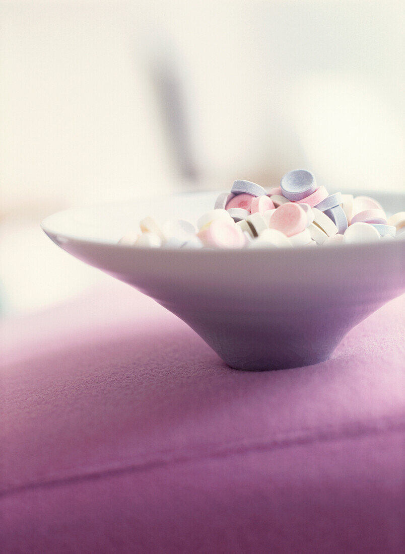 Lila, weiße und rosa Bonbons in einer Keramikschale