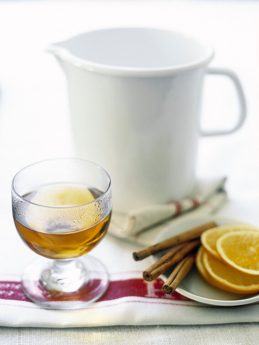 Glass of tea with cinnamon sticks and slices of orange