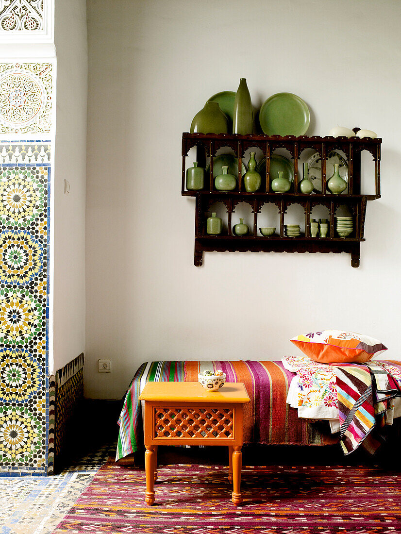 Wandregal mit grüner Keramik über einem Tagesbett in einem marokkanischen Riad in Nordafrika