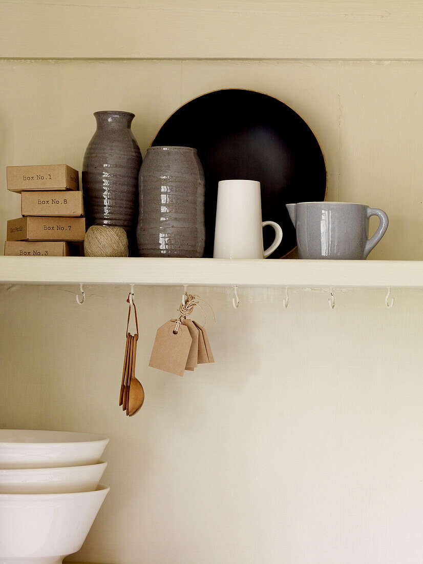 Assorted ceramics with labels and spoons on shelf