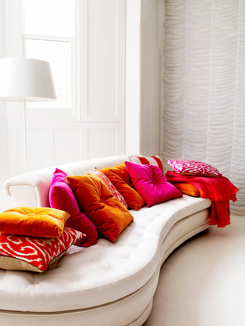 White sofa with assorted pink and orange cushions