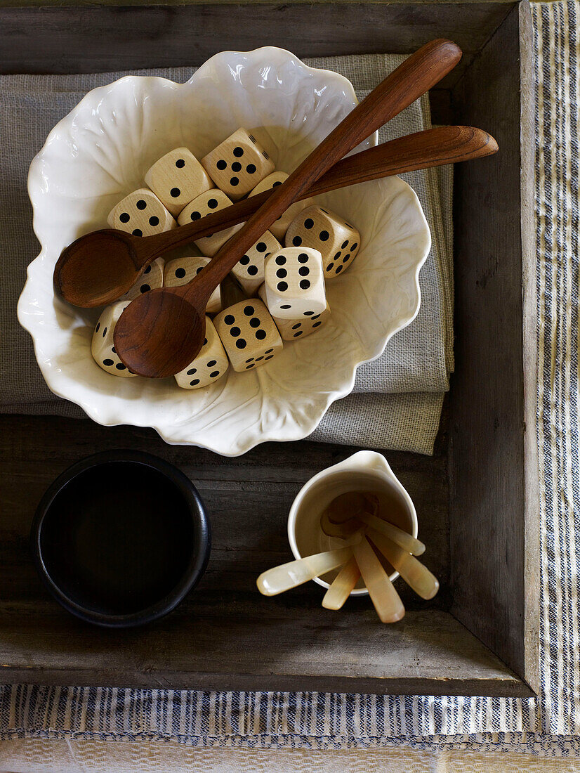 Wooden spoons and dice in ceramic bowl in crate