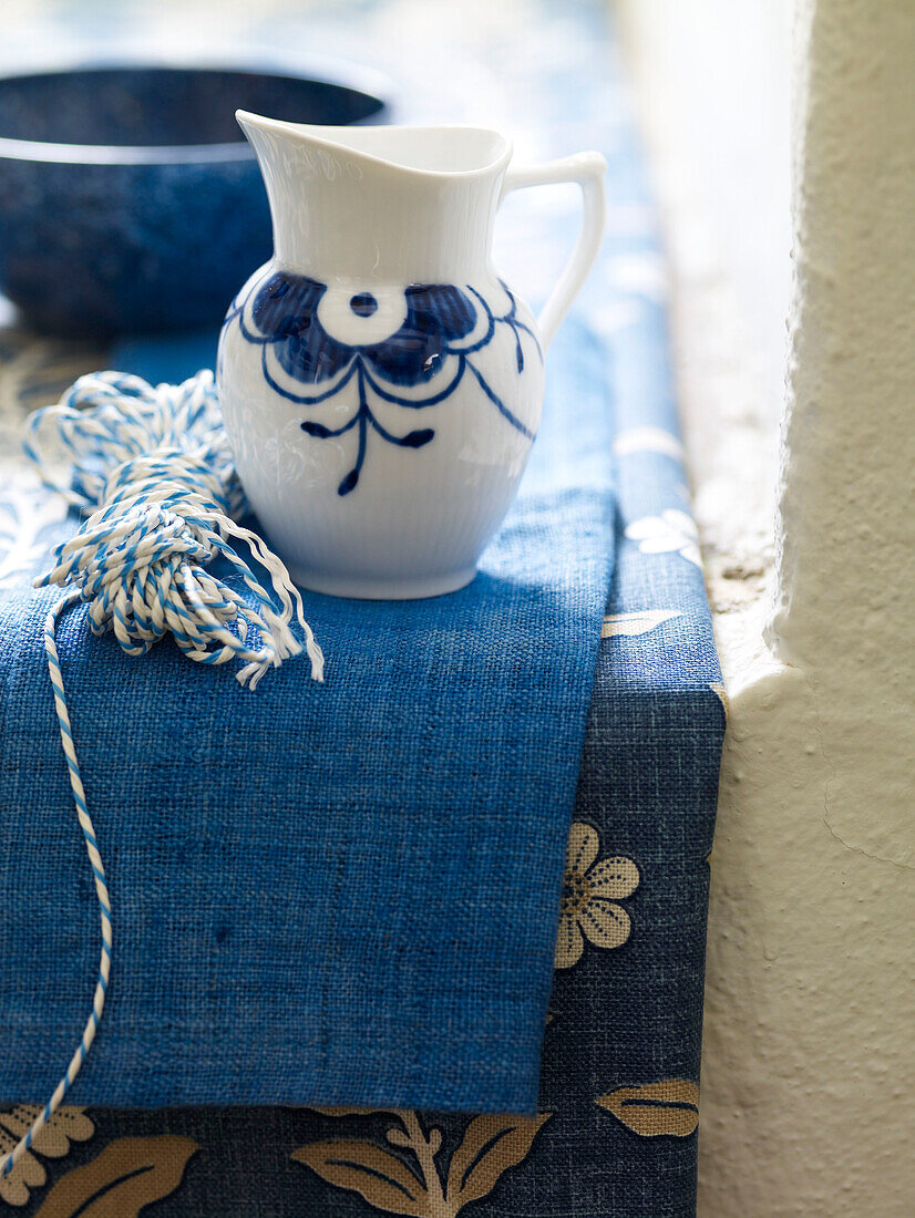 Blue and white jug with string on fabric Spain