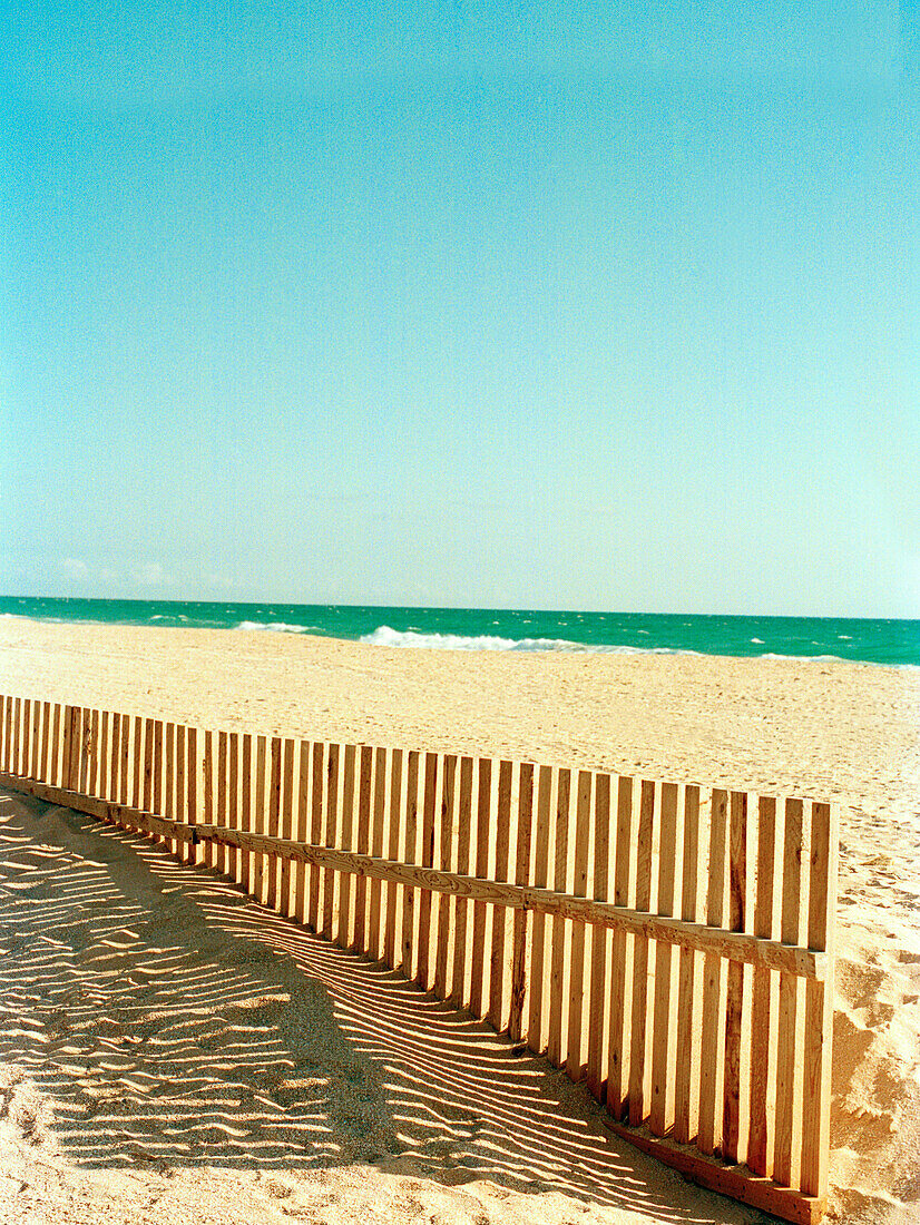 Schatten eines hölzernen Seebrechers am spanischen Sandstrand