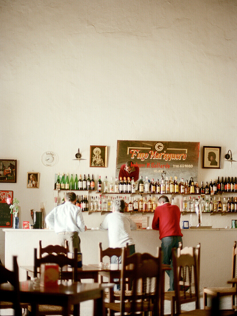 Drei Männer stehen Seite an Seite in einer spanischen Bar