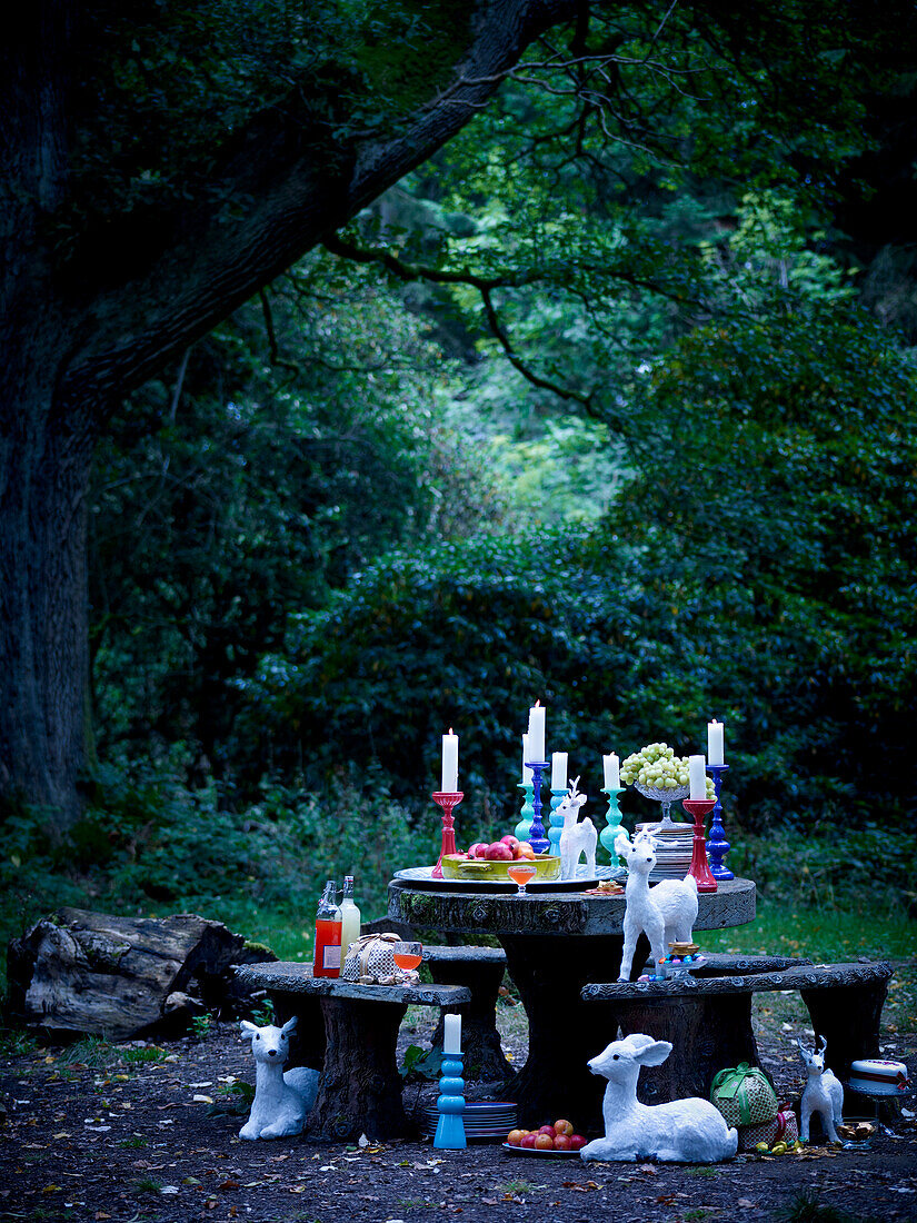 Candlesticks and figurines on table in woodland clearing