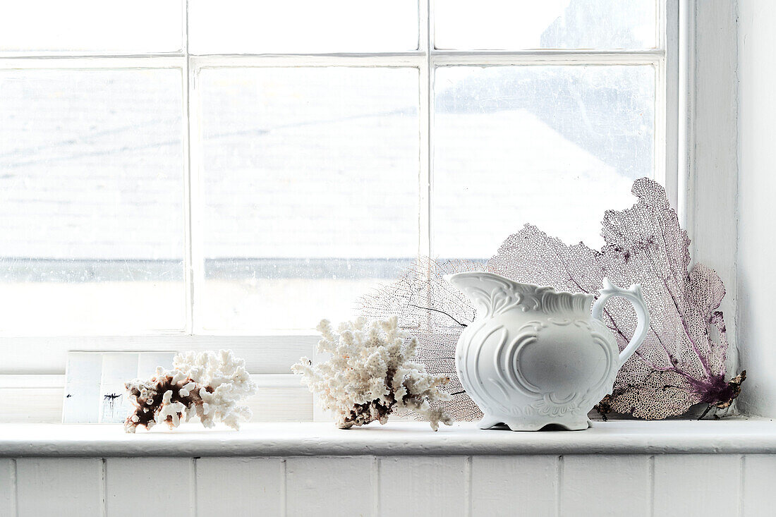 Keramikkrug und Koralle auf der Fensterbank in einem Haus in Lyme Regis, Dorset, UK