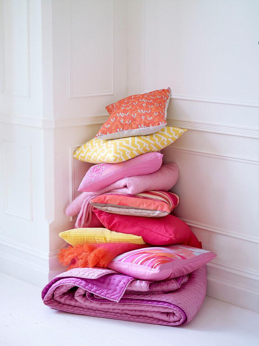 Stacked cushions and folded pink quilt