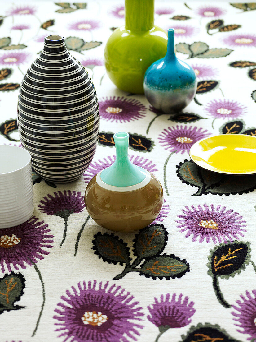 Keramikvasen auf geblümtem Tischtuch
