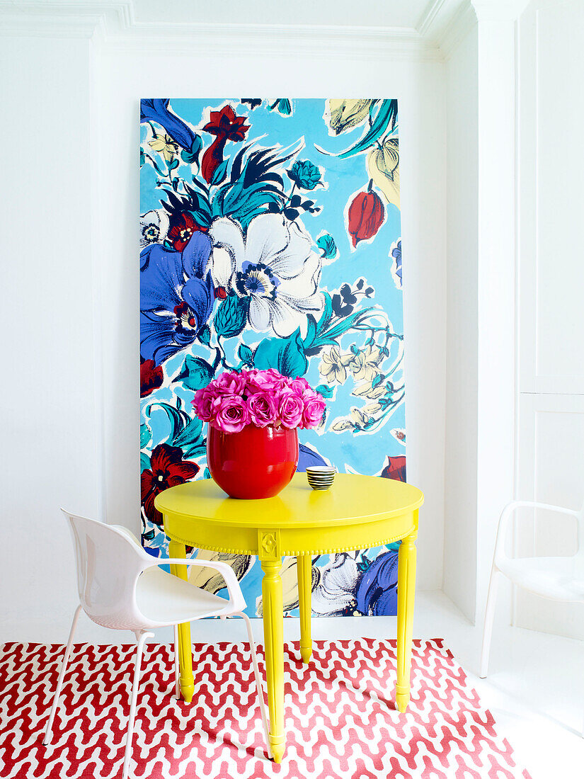 Blumenvase auf gelbem Tisch mit floraler Kunstleinwand