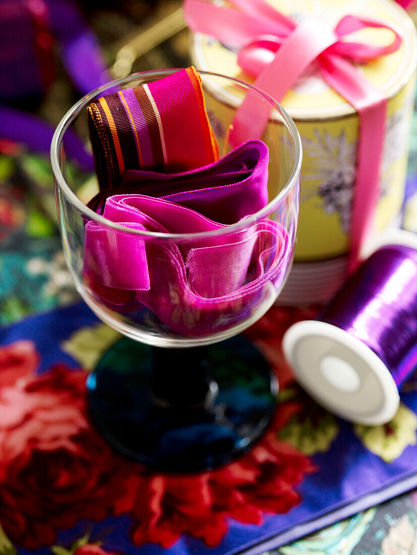 Sortiertes rosa Band in Weinglas mit Garnspule