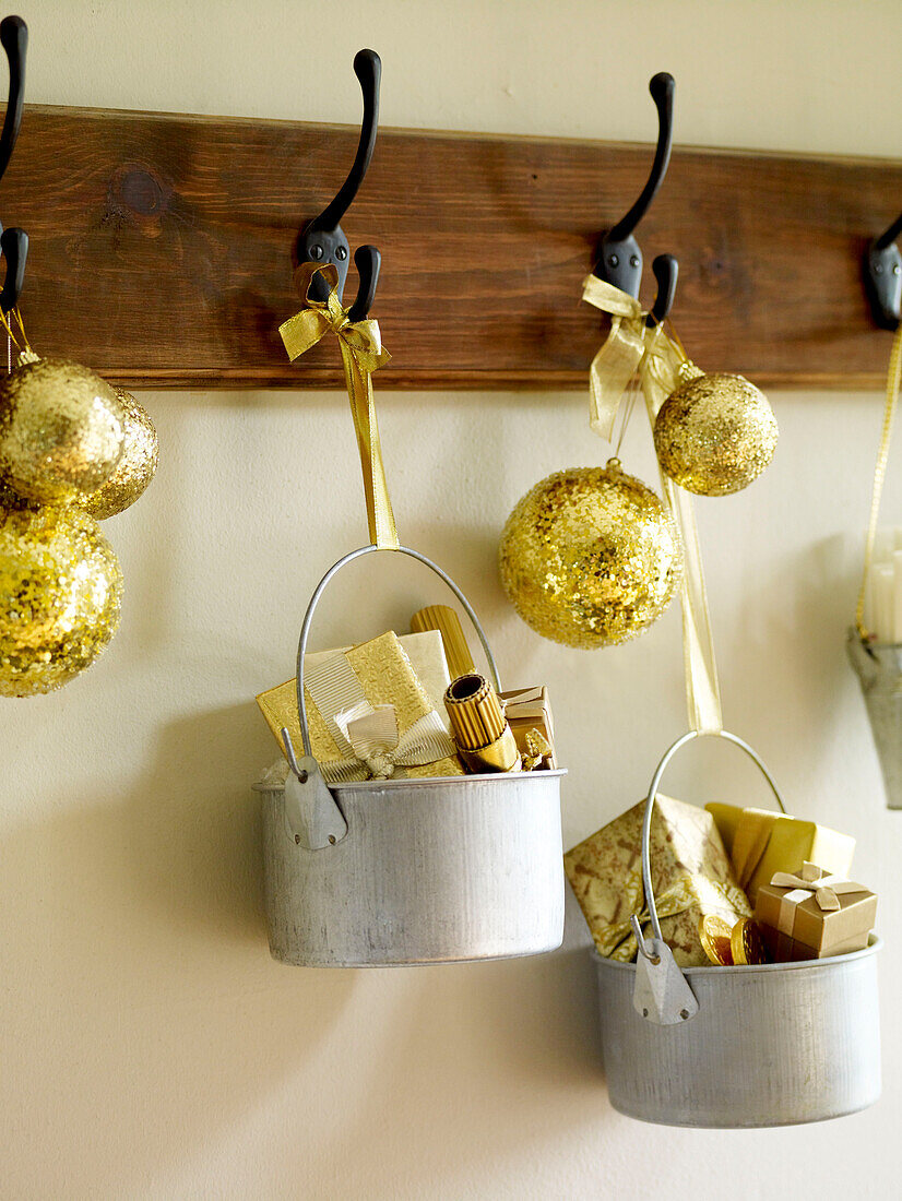 Silver pans full of gifts with gold baubles on coat hooks
