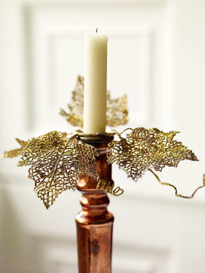 Painted gold leaves decorating single candle