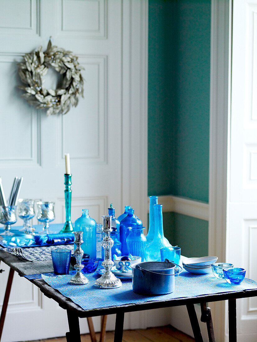 Collection of blue glassware with silver candlesticks on table