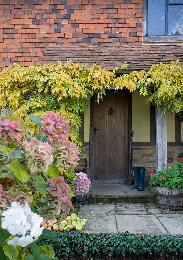 Gummistiefel am Eingang der Veranda eines Familienhauses in Cranbrook, Kent, England, UK