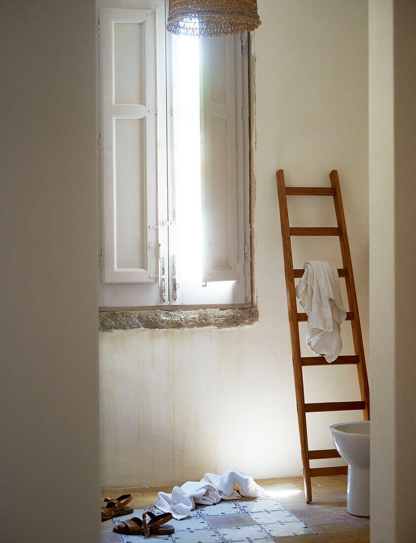 Leiter als Handtuchhalter und Sandalen mit heruntergefallenen Handtüchern in einem sizilianischen Haus