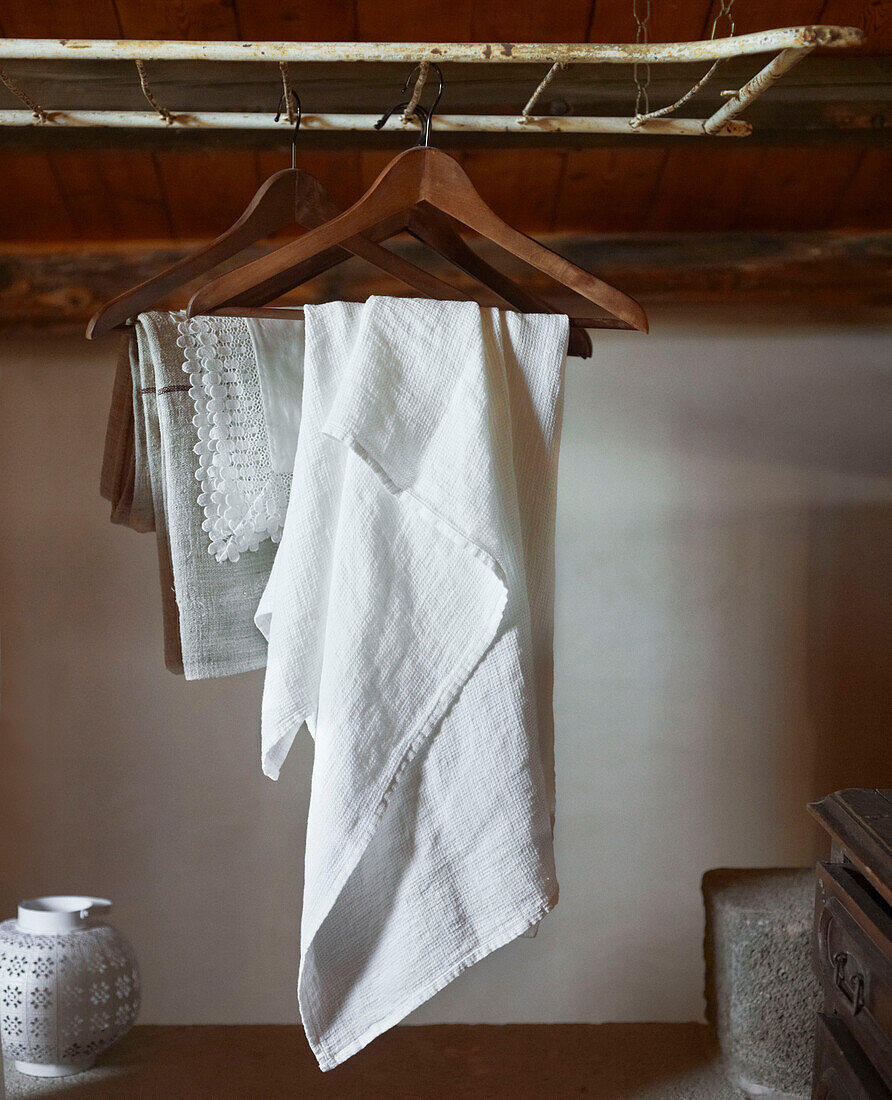 Weißes Leinen und Spitze auf hölzernen Kleiderbügeln in einem sizilianischen Haus