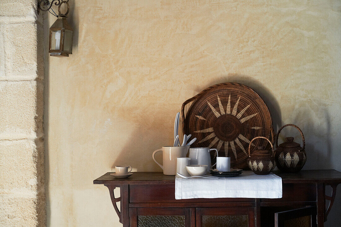 Sonnenschliff-Tablett und Teekannen mit Keramik auf Holzanrichte in einem sizilianischen Haus