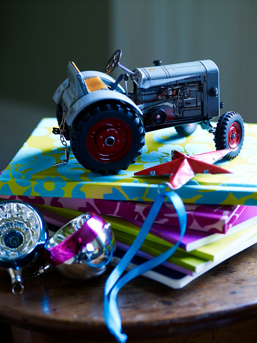 Toy tractor on stack of notebooks with baubles