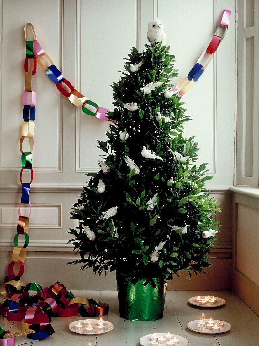 Weihnachtsbaum geschmückt mit weißen Tauben mit metallischer Luftschlange und brennenden Teelichtern