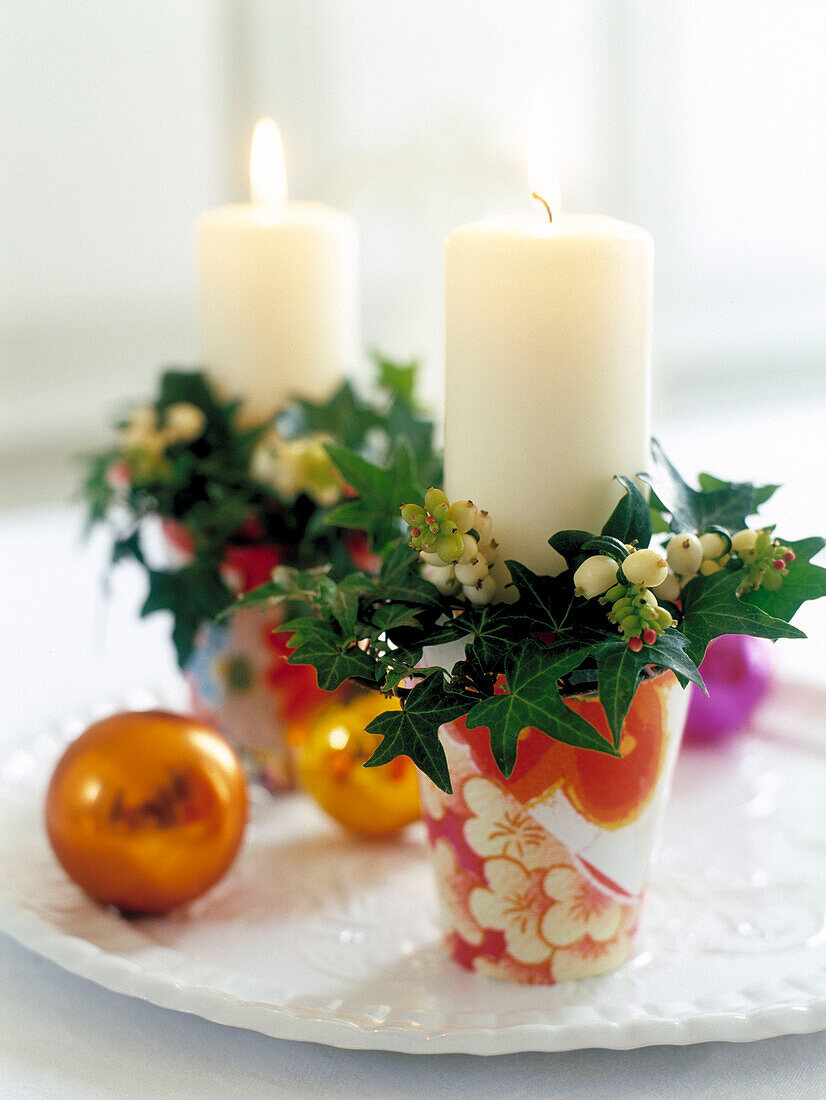 Candles with mistletoe and ivy with gold baubles on plate
