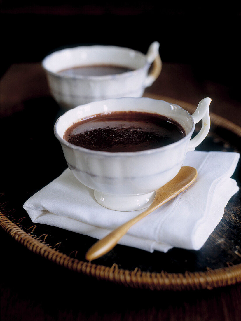 Tasse mit heißer Schokolade und Holzlöffel mit gefalteter Serviette auf einem Tablett