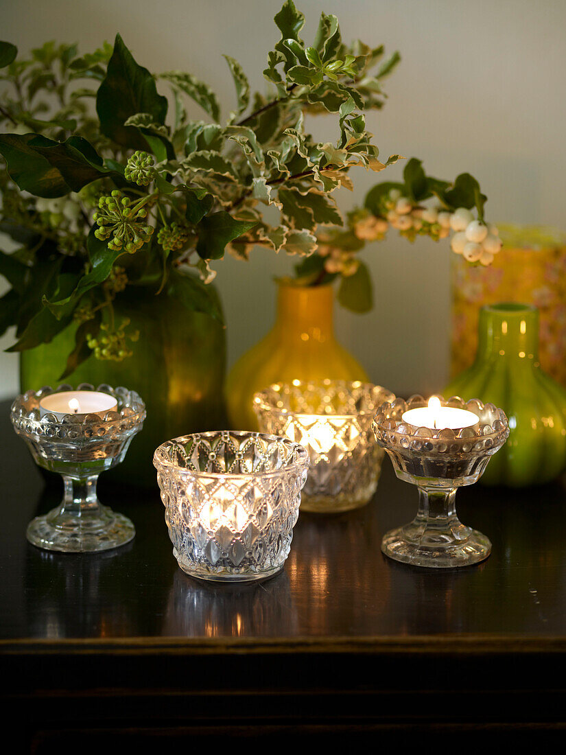 Teelichter aus geschliffenem Glas mit Stechpalme in Keramikvasen