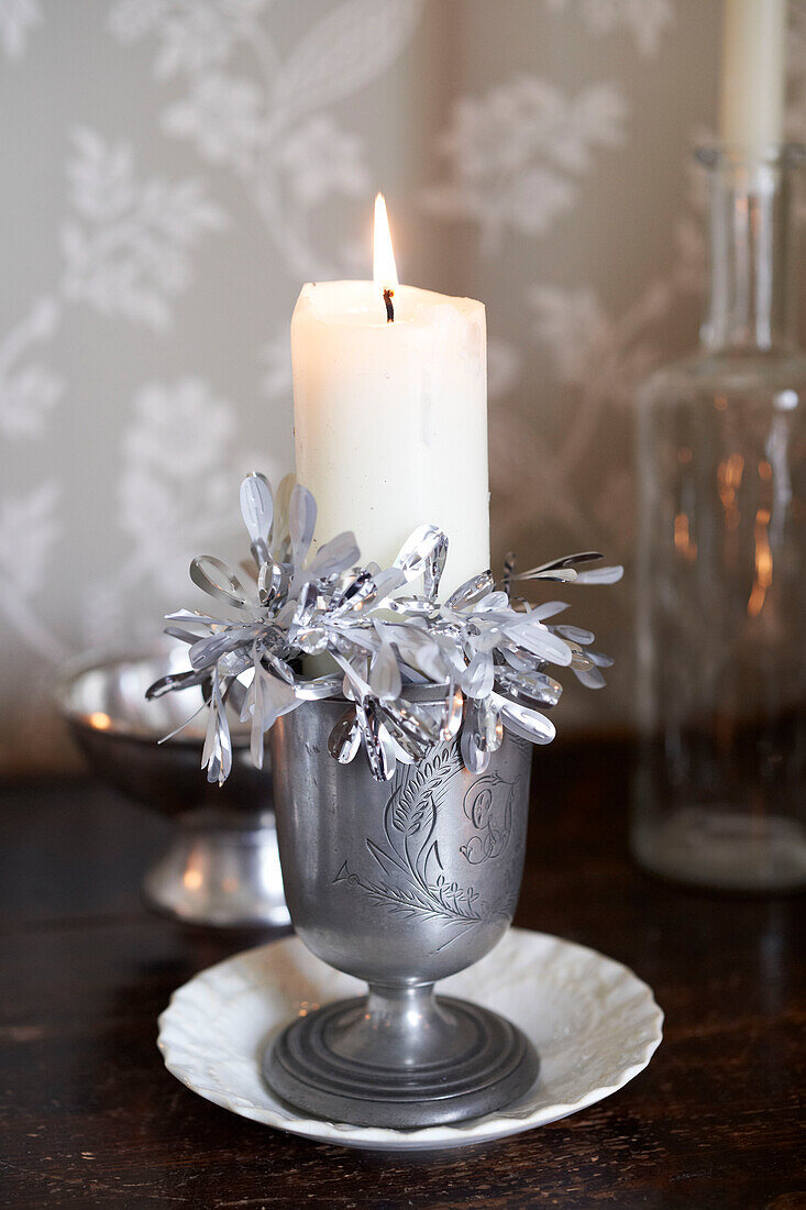 Lit candle with silver tinsel in pewter goblet