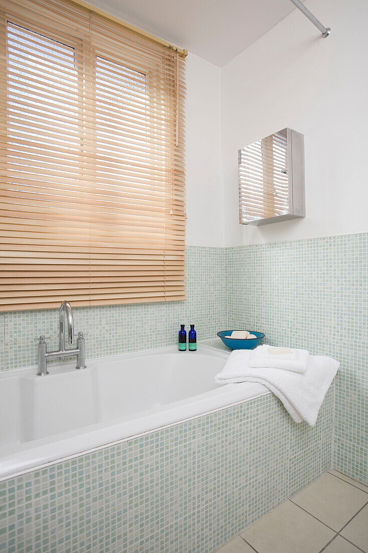 Mosaic tiled bath and window blinds in Manchester home, England, UK