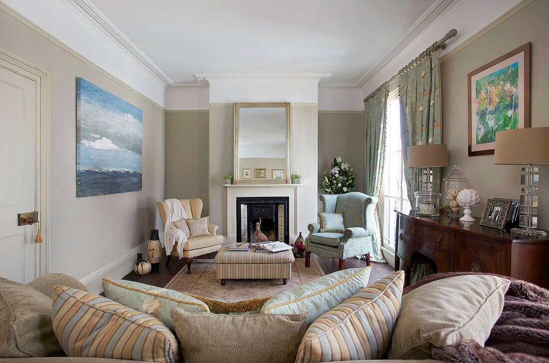 Armchairs at fireplace and artwork in living room of Cranbrook home, Kent, England, UK
