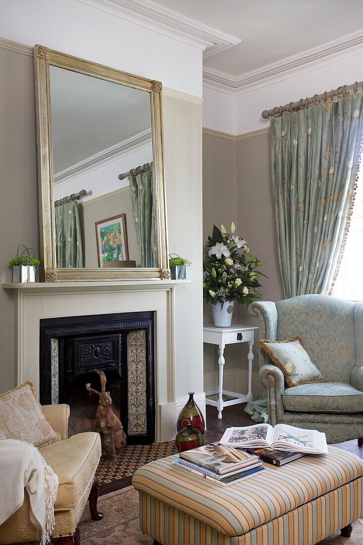 Sessel am Kamin mit übergroßem silbergerahmten Spiegel im Wohnzimmer des Hauses Cranbrook, Kent, England, UK