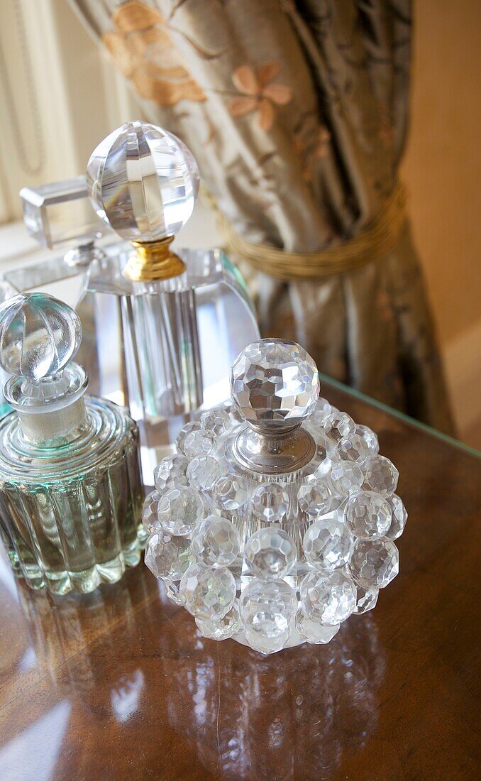 Vintage perfume bottles on side table in bedroom of Cranbrook home, Kent, England, UK