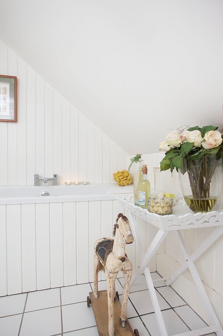 Rocking horse and cut yellow roses in bathroom of Cranbrook home, Kent, England, UK