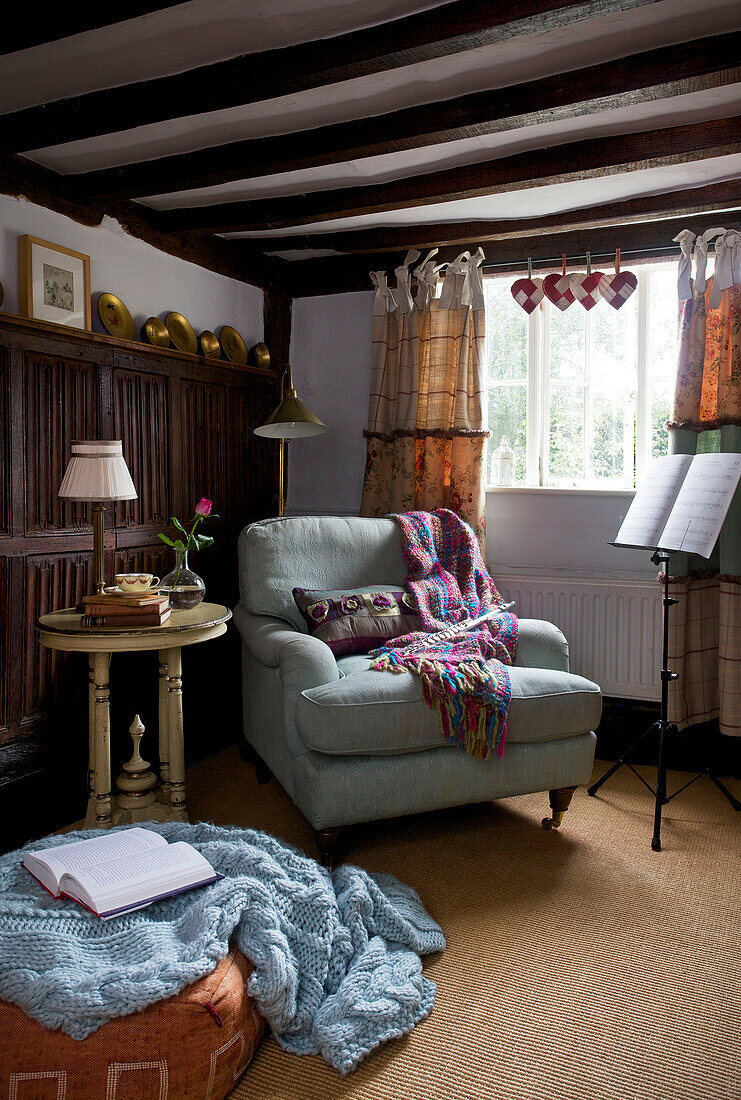 Hellblauer Sessel mit Decke und Notenständer in einer Ecke von Sandhurst cottage, Kent, England, Vereinigtes Königreich