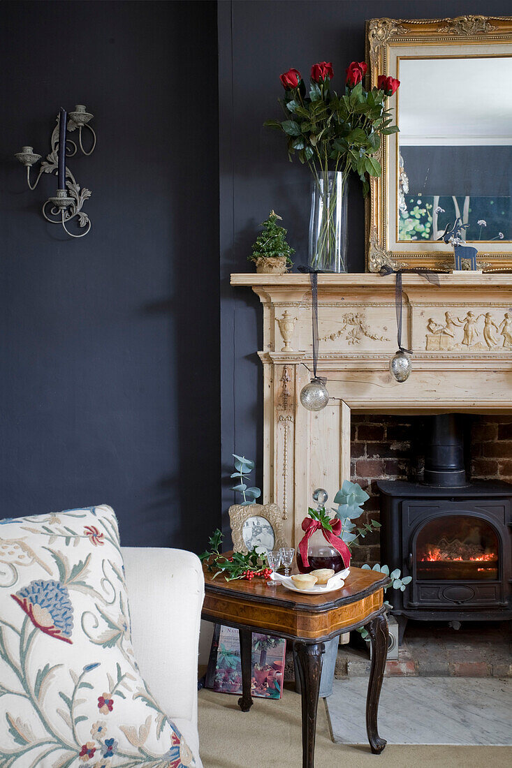 Cut roses on mantlepiece in dark grey living room with woodburning stove in Tenterden home, Kent, England, UK
