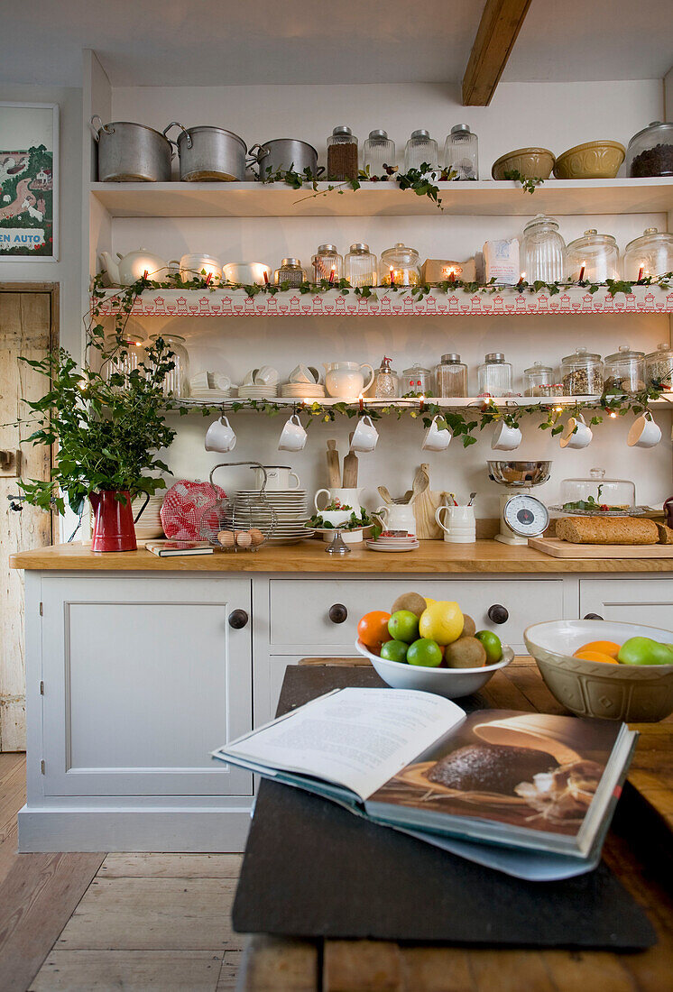 Kitchen ware and lit candles with Christmas greenery in kitchen of Tenterden home, Kent, England, UK