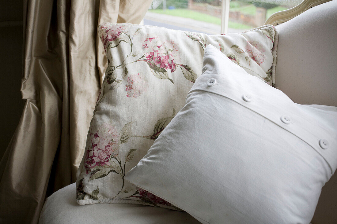 Floral and plain patterned cushions on armchair in Tenterden home, Kent, England, UK