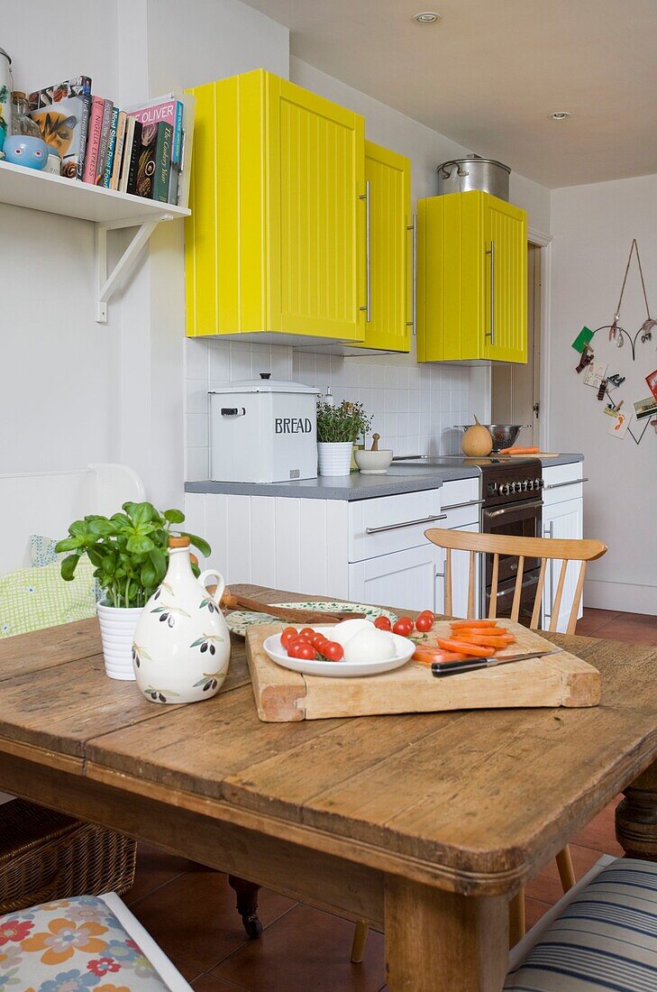 Aufgeschnittene Tomaten und Mozzarella in einer Küche mit gelben Küchenschränken, Familienhaus in Tenterden, Kent, England, Vereinigtes Königreich