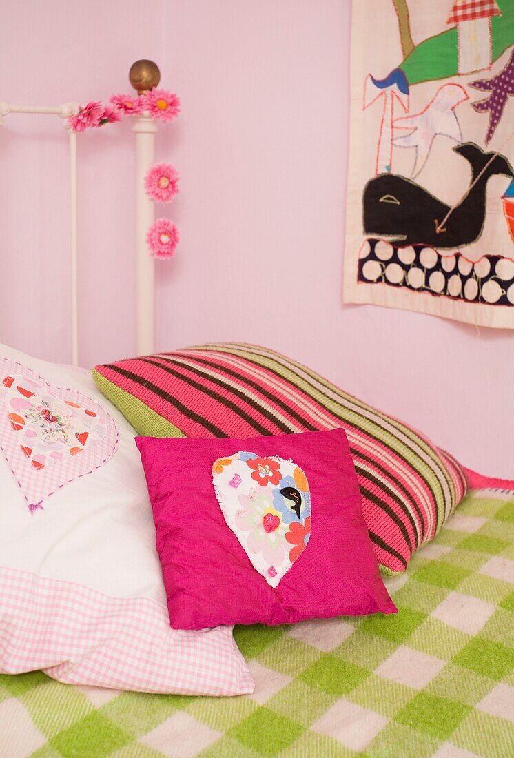 PInk and green soft cushions on girl's bed in Tenterden, Kent, England, UK