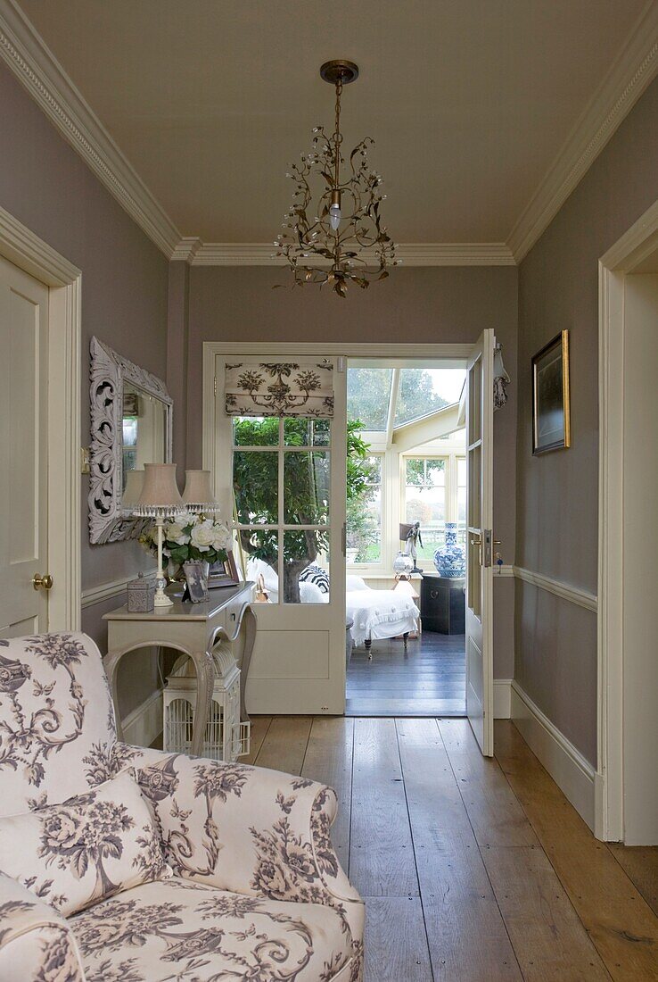 Upholstered armchair in hallway of Grafty Green home, with view to conservatory, Kent, England, UK