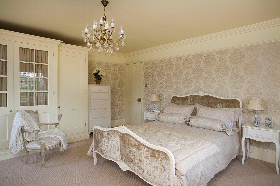 Velvet footboard in bed in neutral master bedroom of timber framed cottage, Grafty Green, Kent, England, UK