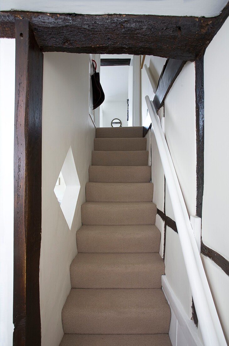 Carpeted staircase in timber framed cottage
