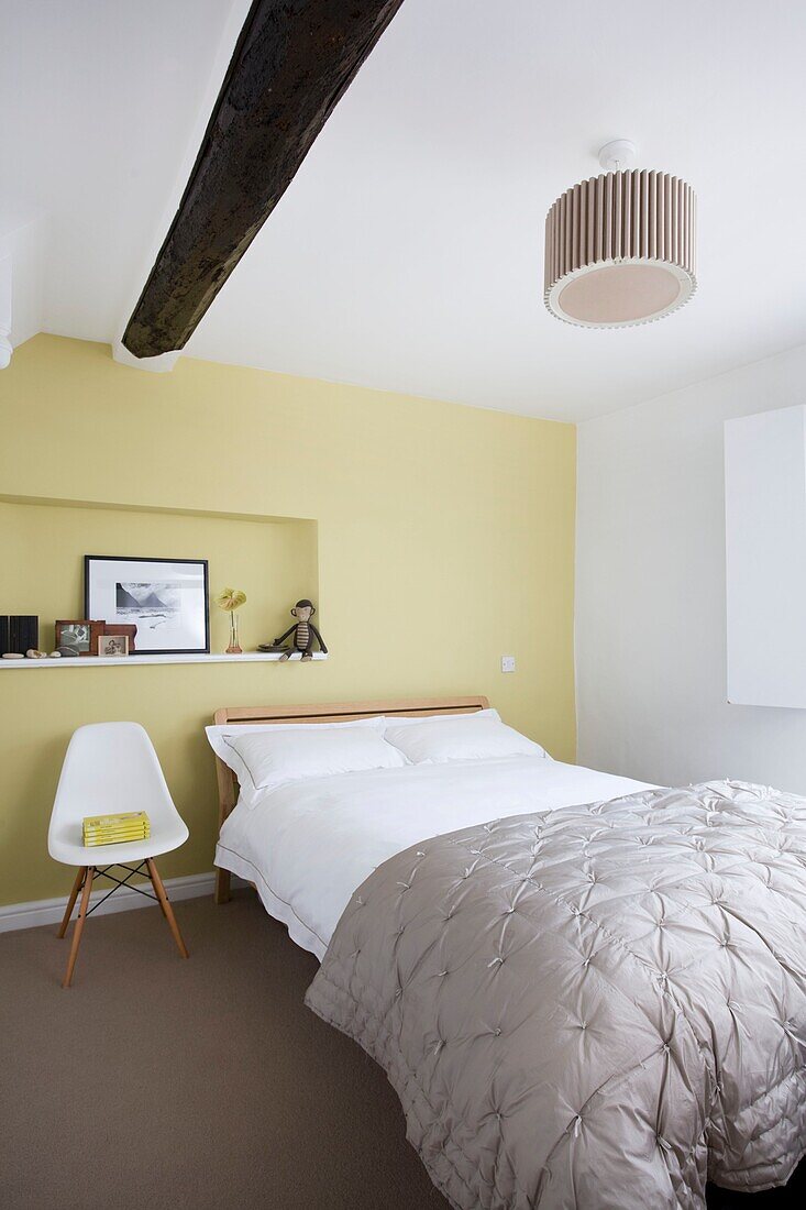 Single bed with grey quilt in yellow bedroom of timber framed cottage