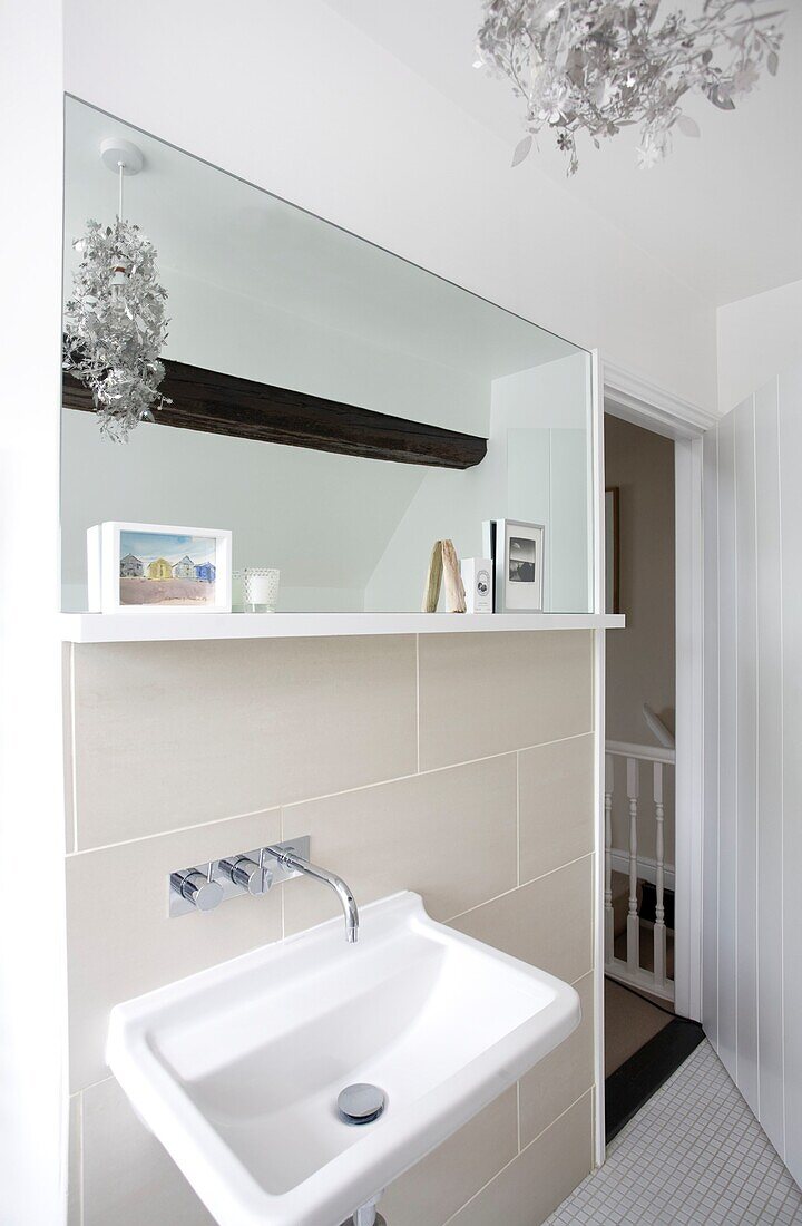 Washbasin below rectangular bathroom mirror in timber framed cottage